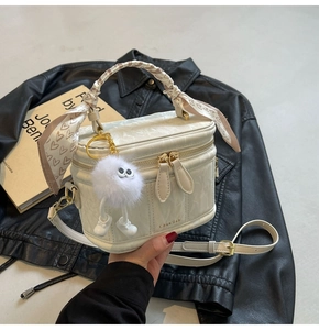 Detailed shot of white quilted box bag with heart print scarf and plush doll charm