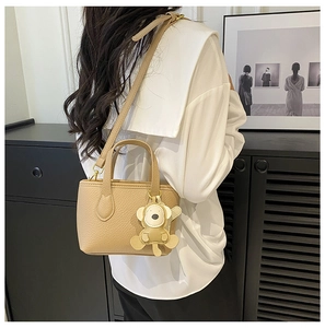 Detail of light khaki lychee pattern bucket bag with cute cartoon monkey charm