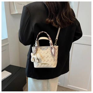 Detail of cream bucket bag with horse pattern, decorative scarf and plush puppy charm