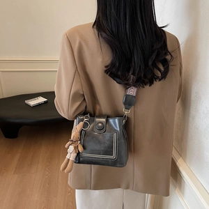 Detalle de bolso cubo en cuero negro con correa tejida y un lindo colgante de conejo