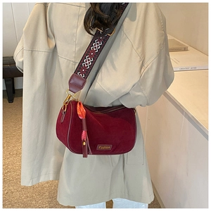 Detail of burgundy crossbody bag with wide vintage patterned strap and silk ribbon