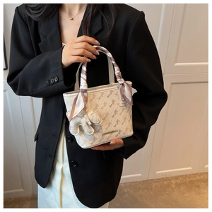 Detail of cream crossbody bucket bag with carriage print and silk scarf handle