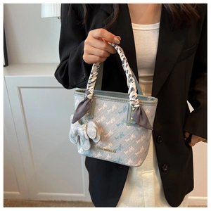 Close-up of light blue handbag with silk scarf handle and elephant charm detail