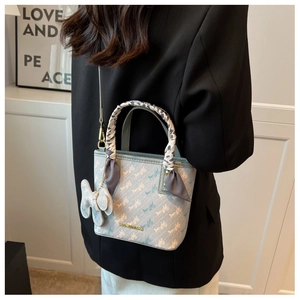 Model wearing a light blue crossbody bucket bag with horse print and leopard silk scarf