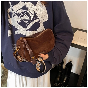 Detail of vintage dark brown pillow bag with jacquard strap and suede finish worn by model