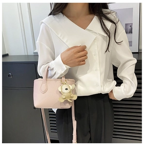 Close-up of pink litchi grain bucket bag worn with shoulder strap in modern setting
