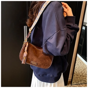 Detail of vintage brown suede pillow bag with jacquard strap and gold metallic logo