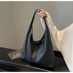 Nahaufnahme einer schwarzen Hobo-Tasche aus Leder mit Lychee-Muster auf einem Schreibtisch