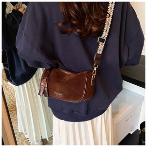 Detail of dark brown suede cylinder bag with vintage geometric patterned wide strap