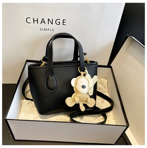 Detail of black litchi grain mini bucket bag with a cute monkey charm in a gift box
