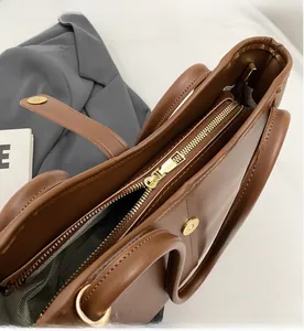 Detail view of smooth golden metal zipper and interior lining of a brown tote bag