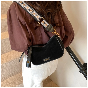 Detail of black suede crescent bag with a colorful ethnic style woven shoulder strap