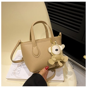 Detail of khaki litchi grain bucket bag with handles and a cute monkey pendant charm
