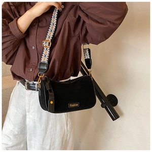 Close-up of black suede pillow bag featuring a woven strap and golden buckle details