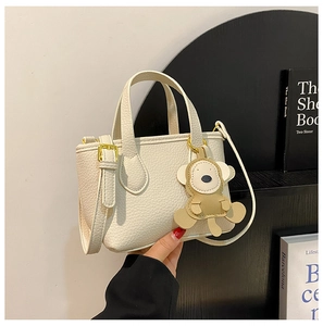 Close-up of cream white lychee texture bucket bag with cute bear charm and gold hardware