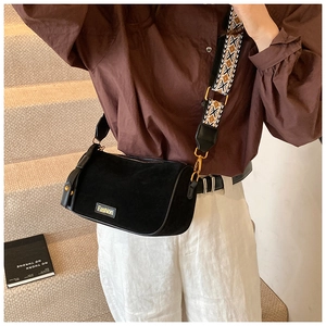 Detail of black suede-like bag with a geometric pattern woven strap and gold hardware