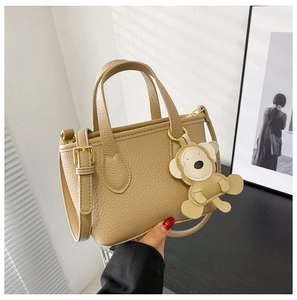 Detail of beige lychee pattern bucket bag featuring a cute monkey leather charm