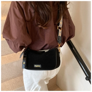 Detail of black suede cylinder bag with Fashion patch and ethnic pattern strap