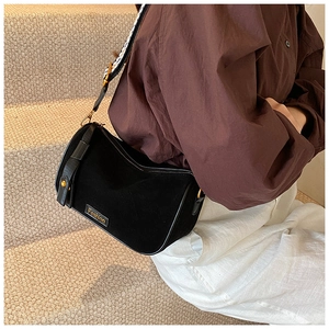 Detail of black suede crossbody bag with fashion tag and woven checkered wide strap