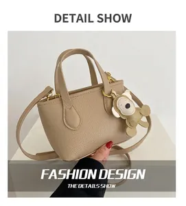 Close-up of beige lychee grain bucket bag with cute bear charm and adjustable strap