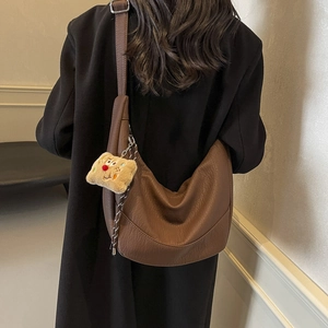 Brown lychee leather crescent bag with plush toast charm shown on a model