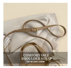Detail of adjustable litchi texture leather strap with gold buckle on brown bucket bag