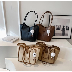 Detail view of four large tote bags in black brown beige and khaki with soft charms