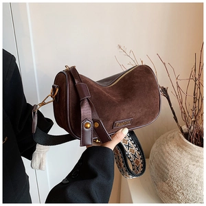 Detail of vintage brown suede boston bag with patterned strap and golden hardware