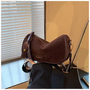 Detail of coffee suede pillow bag featuring a fashion tag and patterned shoulder strap