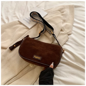 Close-up of retro brown pillow bag with woven strap and vintage golden metal hardware