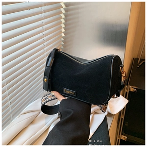 Detail of black suede Boston bag featuring golden hardware and a geometric woven strap