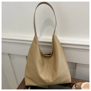 Detail shot of a ginger leather tote bag featuring rich pebble grain texture and sleek strap