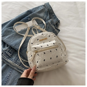 Close-up of white textured backpack with black bird pattern and golden fashion logo