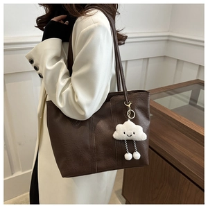 Detail of dark brown tote bag with decorative vertical stitching and plush cloud charm