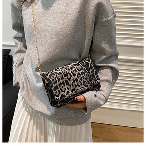 Close-up of leopard print crossbody bag with gold chain strap on a fashion model