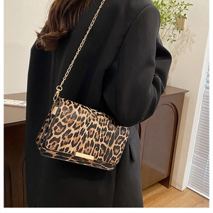 Detail of leopard print shoulder bag with gold chain strap worn by a model in a black blazer