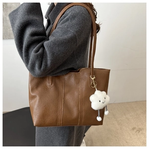 Brown large tote bag with pleated texture and white cloud charm shown on wool coat