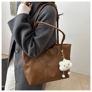 Close-up of retro pleated leather tote bag with a white plush cloud accessory detail