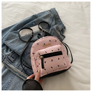 Detailed macro view of pink backpack with black bow print and fashion metal logo
