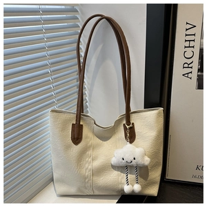 Dettaglio borsa tote off-white con trama a pieghe, manici marroni e ciondolo a nuvola