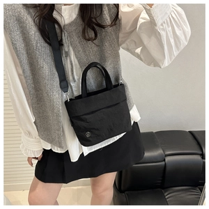 Detail of compact black nylon bucket bag featuring adjustable strap and silver M logo