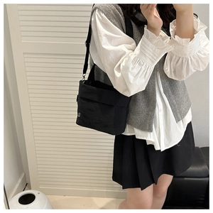 Detailed side view of black nylon bucket bag with adjustable woven shoulder strap