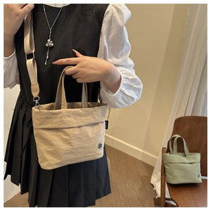Detail of minimalist beige bucket bag featuring wrinkled nylon texture and adjustable strap