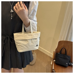 Detail of minimalist cream bucket bag with unique crinkled fabric texture and metal charm