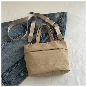 Detalle del bolso tote infantil de nailon caqui con correa ajustable sobre mezclilla