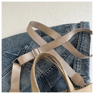 Primer plano detallado de bolso de lona beige con correa ajustable y hebilla plateada