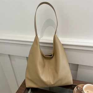 Minimalist beige pebble leather hobo shoulder bag with wide strap on wooden surface