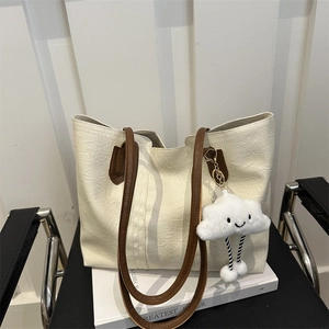 Borsa tote bianco crema con manici marroni e ciondolo di peluche su sedia vintage