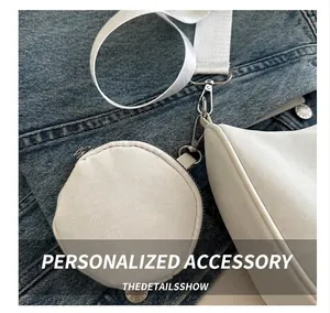 Close-up of white canvas shoulder bag with detachable round coin purse on denim