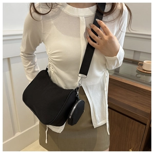 Détail d'un sac bandoulière noir avec sangle large et pochette ronde amovible